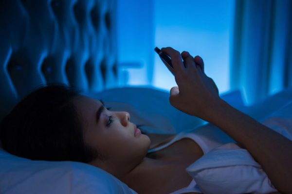 Lady texting at night in bed, interrupting her sleep.