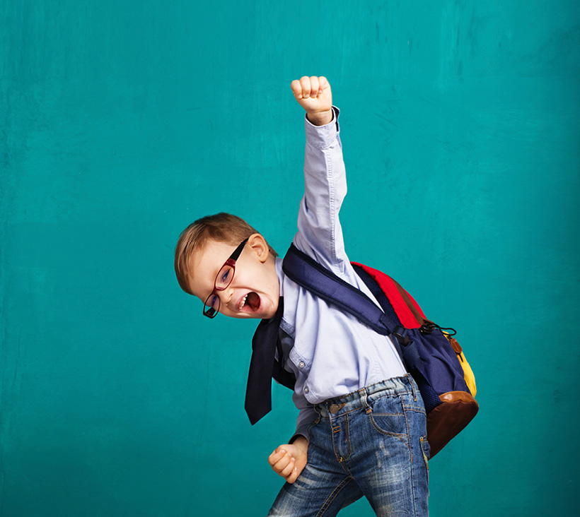 Child with back pack punching fist into air. Chiropractic backpack tips